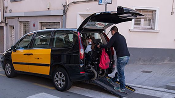 Una persona puja a un taxi en cadira de rodes