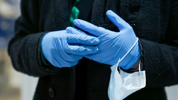 Mans d'una persona amb guants sostenint una mascareta