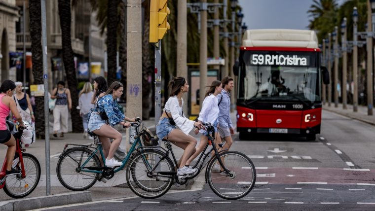 Un grup de persones en bici creuen un pas davant un autobús urbà aturat.