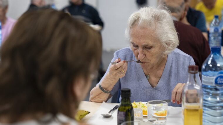 Una dona gran menja a l'Espai de Gent Gran de l'Esquerra de l'Eixample en el marc del programa "Àpats en companyia"