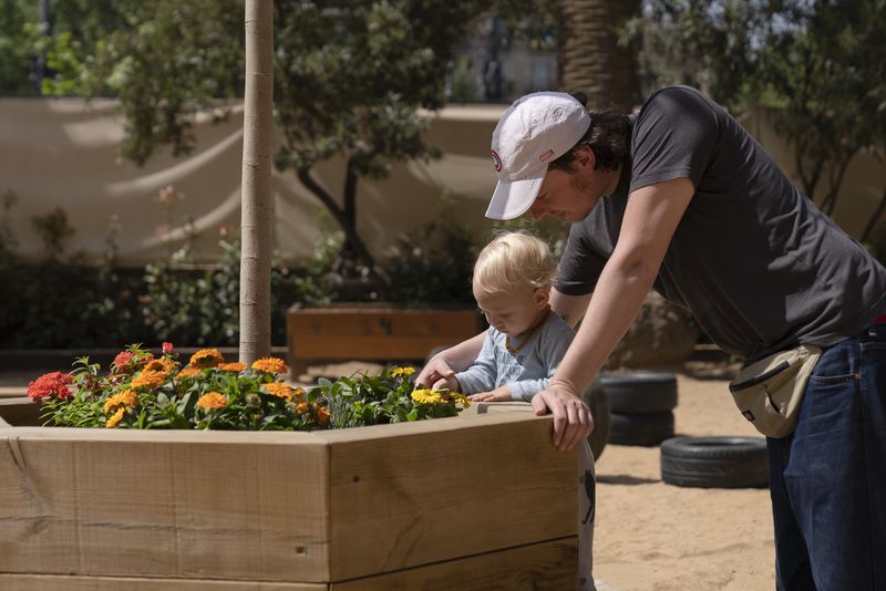 un pare amb el seu nadó miren un parterre amb flors