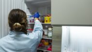 Una científica agafa uns vials d'un armariet a un laboratori