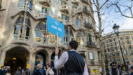 Turistes davant de la Casa Batlló amb un informador mostrant una cartell on es llegeix "Ask Me"