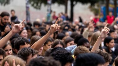 Diverses, demanant la paraula, alçades entre un grup de persones.