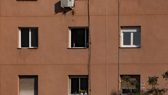 Façana d'un edifici amb gent mirant per la finestra.