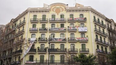 La façana de la Casa Orsola, a l&#039;encreuament dels carrers Consell de Cent i Calàbria, plena de pancartes contra el desnonament de les veïnes que hi resideixen.