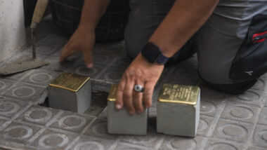 Un home col·loca els Stolpersteine en memòria dels germans Sariñena davant el seu darrer domicili a Comtes de Bell-Lloch,125. Autor: Isaac Carbonell