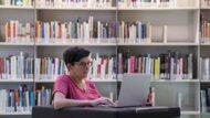 persona fent servir un ordinador portàtil en una biblioteca.