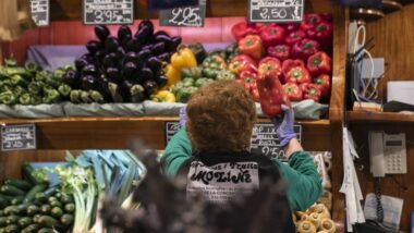 Una treballadora d&#039;una fruiteria endreça els productes en una estanteria.