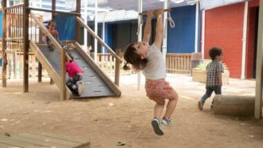 Nena penjada d&#039;una barra fent equilibris a una EBM. Autora: Joanna Chichelnitzky.
