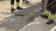 Dos obrers amb dos rastells treballant sobre el paviment