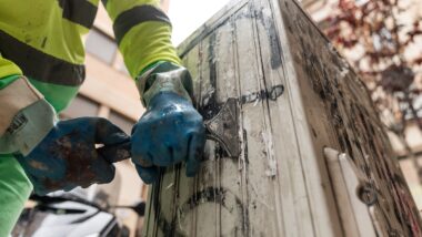 Un treballador del servei de neteja retira papers i adhesius enganxats a una caixa de registre