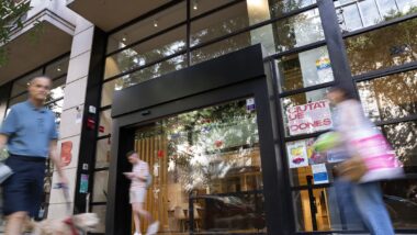 Vista general de l’entrada del centre LGTBI de Barcelona, en el moment en què passen tres ciutadans i un gos. Autor: Àlex Losada.