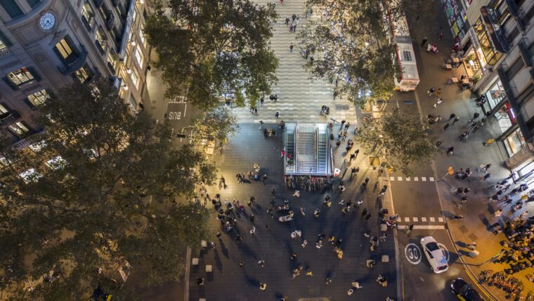 Imatge des de l'aire de la Rambla de Barcelona amb plaça Catalunya. És de nit i es veu gent caminant.