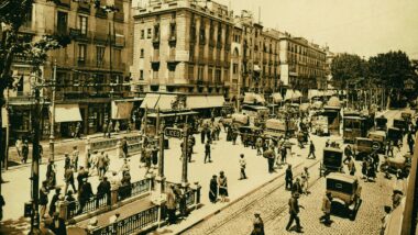 1925. Rambla de Barcelona en plena activitat urbana: vianants passejant, automòbils i tramvies compartint la calçada empedrada, comerços amb tendals i l’entrada al metro amb el rètol "LICEO". Josep Brangulí Soler, Arxiu Fotogràfic de Barcelona.