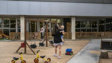Una mare amb un infant al pati obert d&#039;una escola bressol.