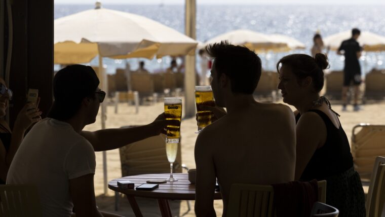 Un grup de persones brinda i beu en una guingueta de platja