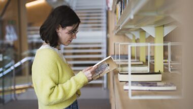 Noia llegeix un llibre en una biblioteca