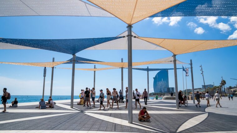 Diferents persones caminant sota les ombres del passeig Marítim de la Barceloneta. Autora: Júlia Arnau.