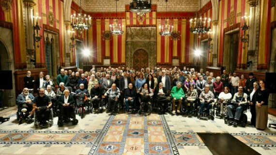 Persones reunides en una sala d'actes. Algunes d'elles estan en cadira de rodes.