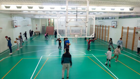 Un grup gran de nens i nenes juguen a bàsquet al pavelló de l'institut i escola Elisabets. Autor: Àlex Losada