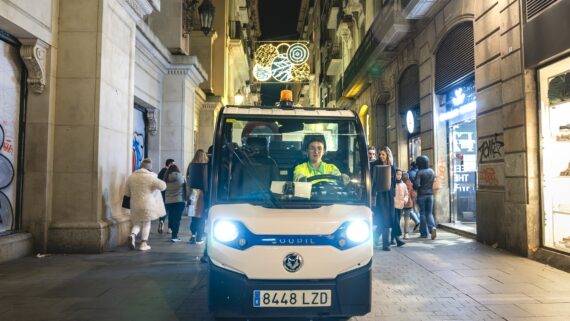 Una persona del servei de neteja condueix el seu vehicle per un carrer guarnit de Nadal