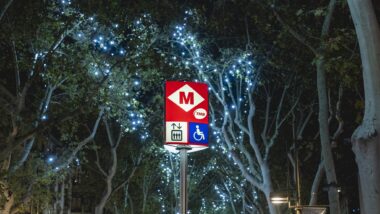 Un senyal de Metro amb arbres decorats de Nadal al darrera