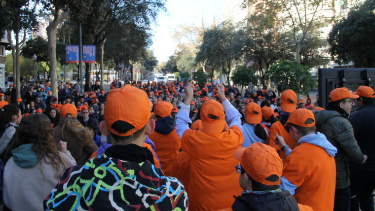 Persones reunides al carrer vestides amb samarretes i gorres de color taronja per festejar el Dia Internacional de les Persones amb Discapacitat.