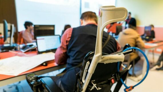 Hombre con discapacidad trabajando en una oficina con otros compañeros