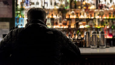 Una persona seu a la barra d'un bar