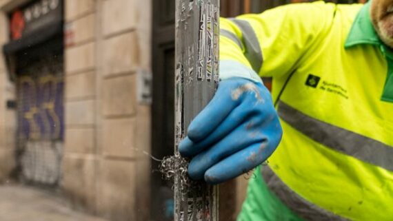 Operari de neteja retirant adhesius d'un element urbà