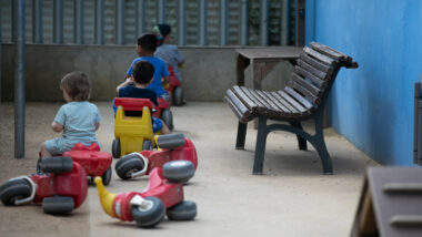Nens jugant amb unes motos de joguina al pati
